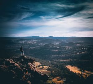 Rear view of man standing on mountain against landscape