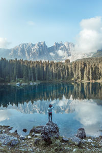 Rear view of man standing on rock by lake