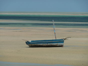 Boat moored on beach against clear sky