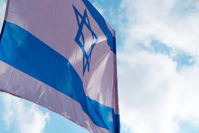 Low angle view of flags against cloudy sky