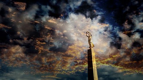 Low angle view of statue against dramatic sky