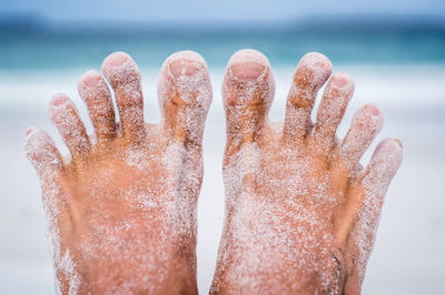 Close-up of human hand against sea