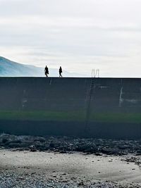 Men standing on shore against sky