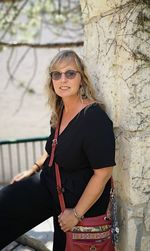 Portrait of mature woman wearing sunglasses while standing against wall