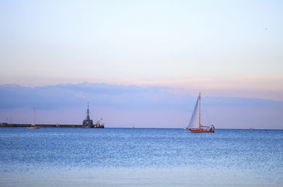 Sailboat sailing on sea against sky during sunset