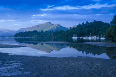 Scenic view of lake by mountains against sky