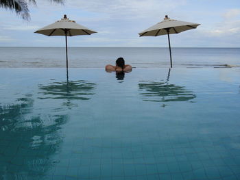 Rear view of woman with umbrella in water