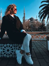 Portrait of young woman standing against wall