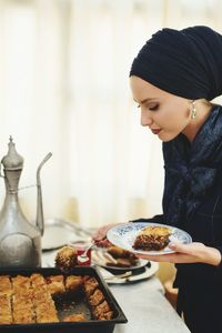 Side view of young woman serving food at cafe