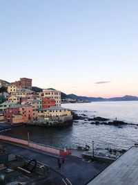 Buildings by sea against clear sky