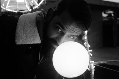 Close-up portrait of man holding illuminated lighting equipment