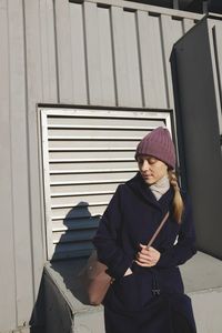 Woman standing against wall in winter