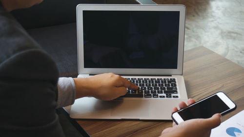 Midsection of man using laptop on table