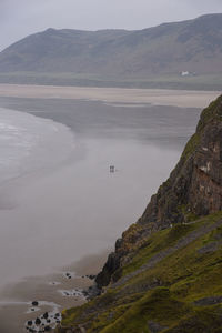 Distant couple walking a dog on deserted beach on a misty day