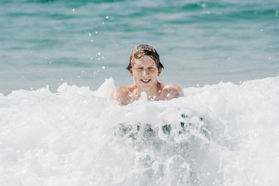 Portrait of smiling shirtless man swimming in sea