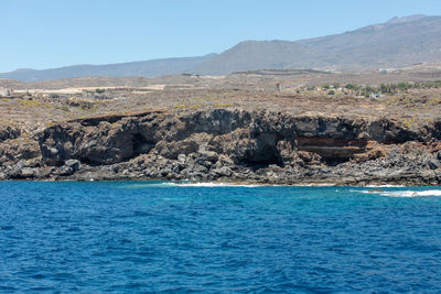 Scenic view of sea and mountains against blue sky