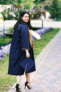 Portrait of a smiling young woman standing on footpath