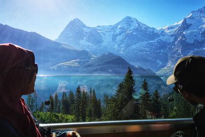 Rear view of people on snowcapped mountains against sky