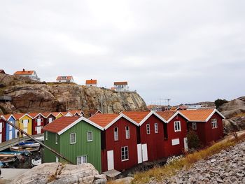 Houses by buildings in town against sky