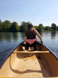 Rear view of woman sitting on boat in lake against sky