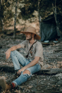 Full length of man sitting on field in forest