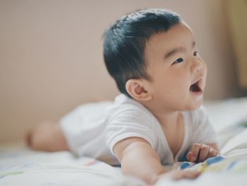 Portrait of cute baby girl lying on bed at home