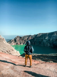 Rear view of man looking at mountain against clear sky