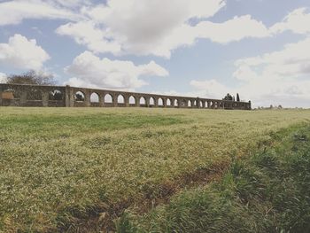 Arch bridge on field against sky