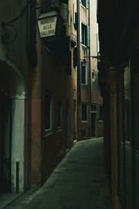 Empty alley amidst buildings in city at night