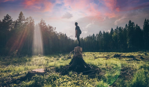 Man standing on field against sky during sunset