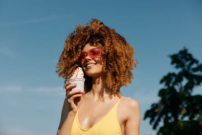 Portrait of young woman looking away against sky