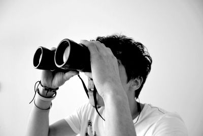 Man looking through binoculars against white background