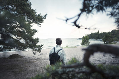 Rear view of man looking at sea against sky