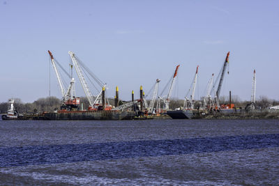 Crane at harbor on sea against sky