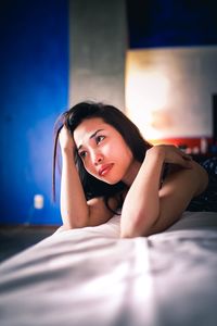 Portrait of young woman lying on bed