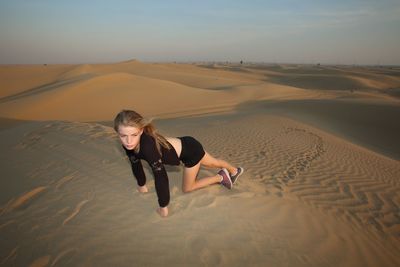 High angle view of girl looking away crawling on desert