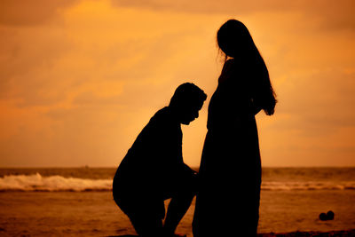 Silhouette couple on beach during sunset