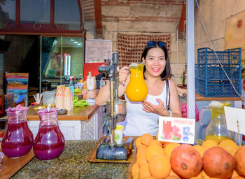 Portrait of smiling woman juice while standing in market