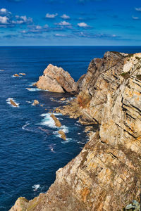 Rock formations by sea against blue sky