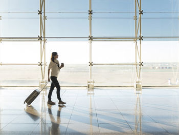 Woman walking with suitcase at the departure hall of the airport.