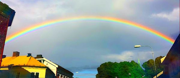 Rainbow over trees against dramatic sky