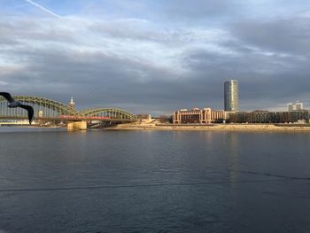 Illuminated bridge over river against cloudy sky