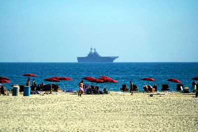 People on beach against clear sky
