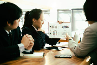 Colleagues discussing over graph at desk in office