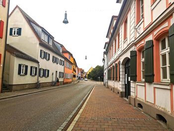 Empty road amidst buildings against sky