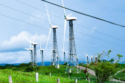 Low angle view of electricity pylon on field