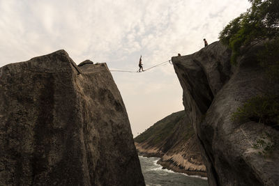 Low angle view of person on cliff against sky