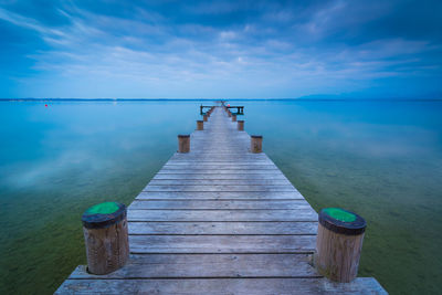 Wooden jetty on pier over sea against sky