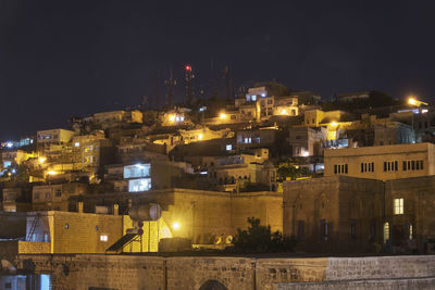 Illuminated buildings in city against sky at night