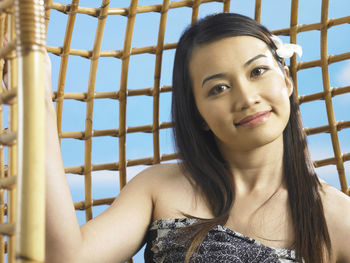 Close-up portrait of smiling young woman sitting on swing